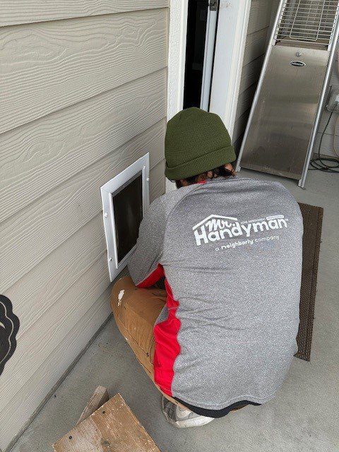 A Mr. Handyman technician installing a pet door into a wall in Nampa, ID.