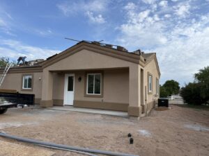 A handyman installing roof tiles and applying stucco to a house exterior for Dahlman Construction in San Tan Valley, AZ.
