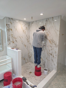 A handyman installing new tiles in a shower during a renovation project by SG Homes LLC in Rockville, MD