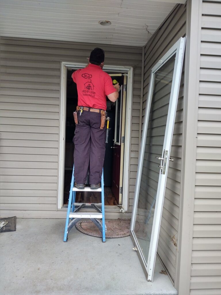 A handyman from IFixdIt Handyman Services in Omaha, NE, installing a new storm door on a residential entryway.