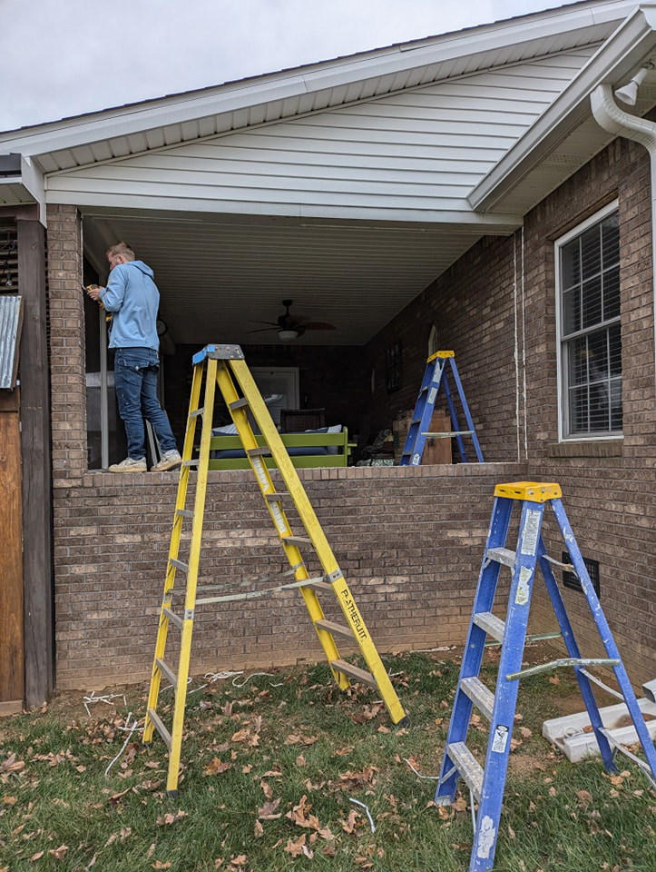 A handyman installing sunroom windows while standing on a ladder for Western Kentucky Sunrooms in Bowling Green, KY.
