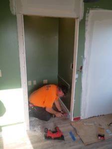 A handyman installing trim around a doorway with a power tool, performing finishing work for NewEra Construction & Solutions in Lexington, KY