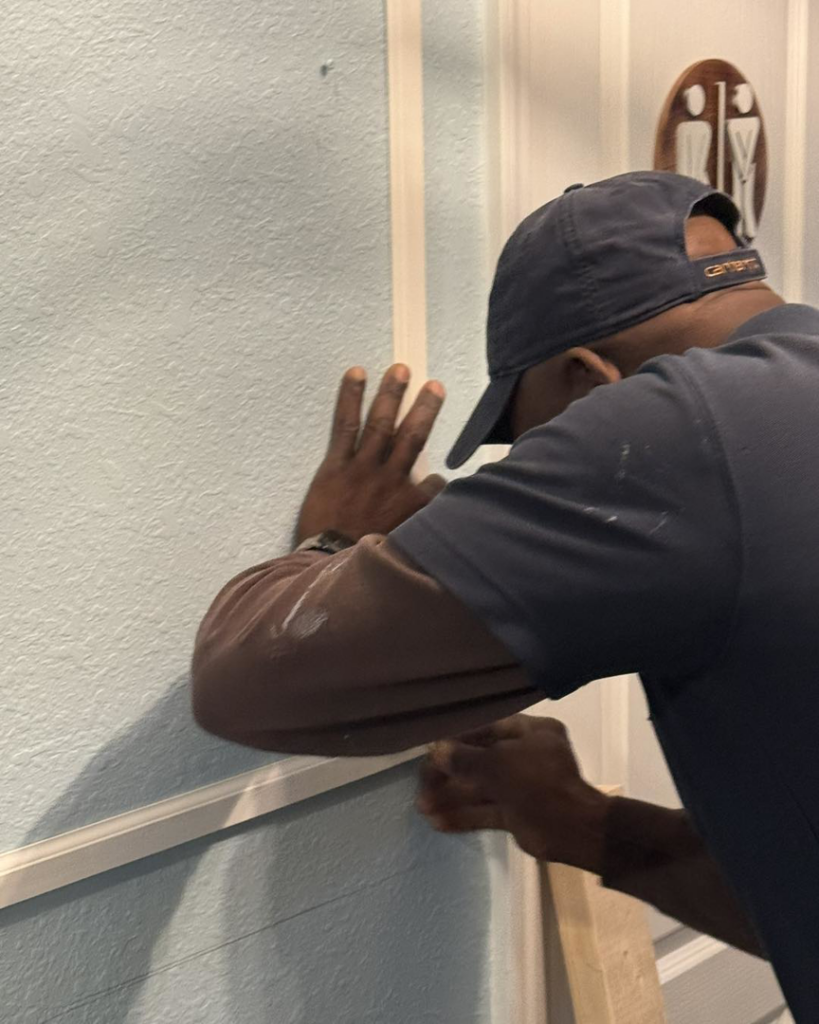 A handyman from Unto GOD's Kingdom Builders precisely installing wall molding and trim in Mint Hill, NC.