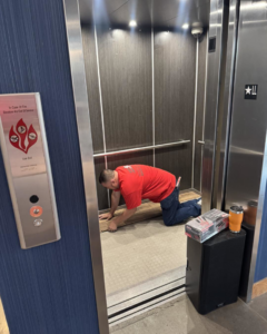 A handyman from Eddie of all trades installing wood-plank flooring inside an elevator in Peoria, AZ.
