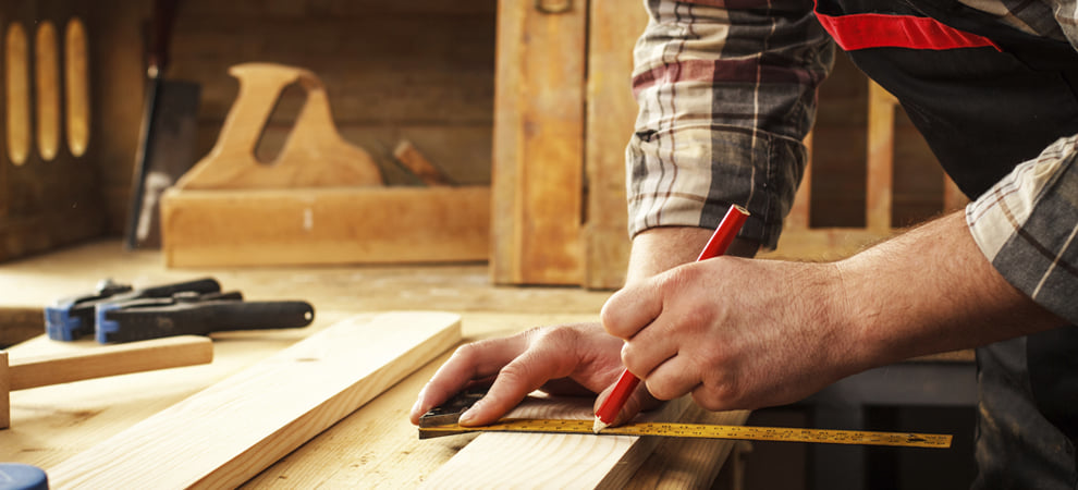 A handyman marking wood with a ruler and pencil for a carpentry project by Lincoln Handyman Services, Lincoln, NE.