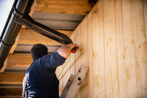 A handyman on a ladder measuring a gutter for exterior repair or installation by Keystone Builders Inc in Milwaukee, WI