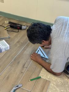 A handyman measuring and preparing laminate flooring planks for installation by Wheeler's Handyman Services in Vermillion, SD