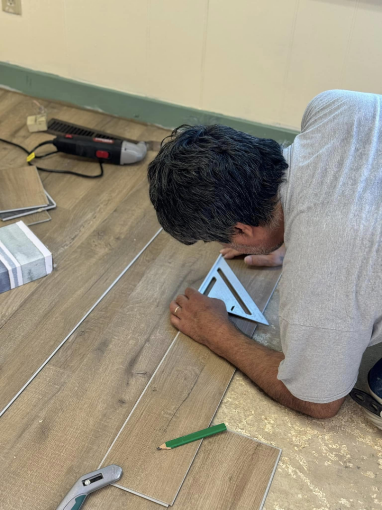 A handyman measuring and preparing laminate flooring planks for installation by Wheeler's Handyman Services in Vermillion, SD