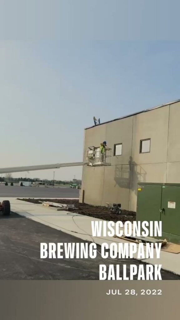 A handyman from Blair Commercial Painting LLC on a boom lift performing exterior maintenance on a commercial building in Waukesha, WI.