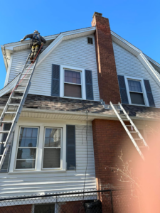 A handyman on a ladder performing roof or chimney repair for Rambo'S Construction Inc in Brockton, MA