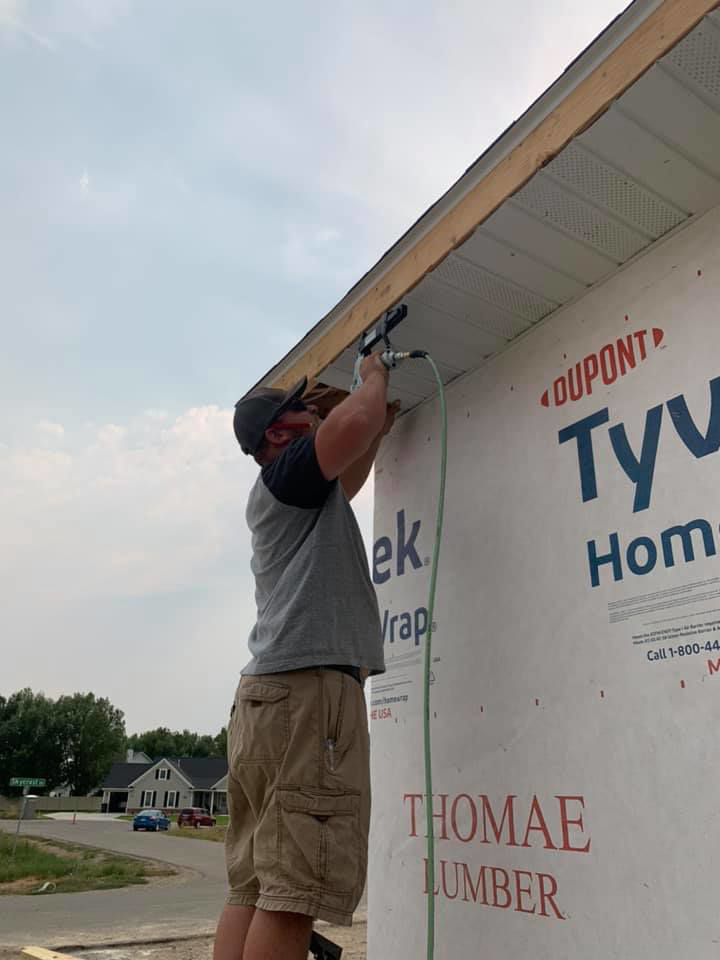 A handyman on a ladder installing siding with a nail gun for Simmons Handyman Services & Contracting LLC in Billings, MT