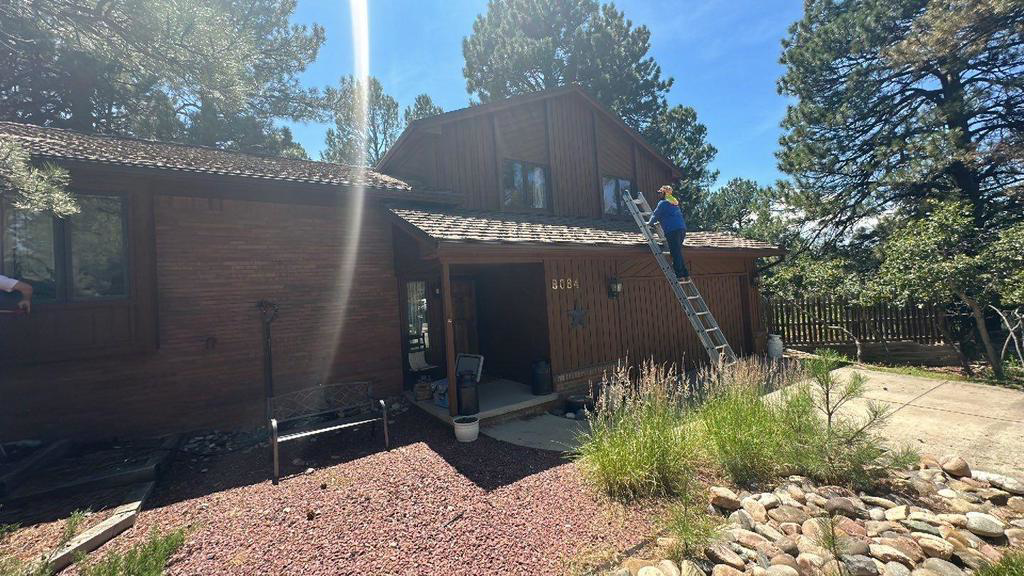 A handyman on a ladder performing repairs on the side of a house for Grayson General Contracting in Parker, CO.