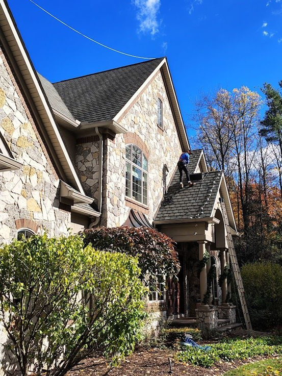 A handyman on a roof installing Christmas lights on a residential home for Ohio Holiday Lighting in Akron, OH.