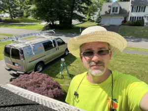 A handyman on a roof, with a power washing van, working for Corriveau Home Improvement LLC in Bristol, CT.