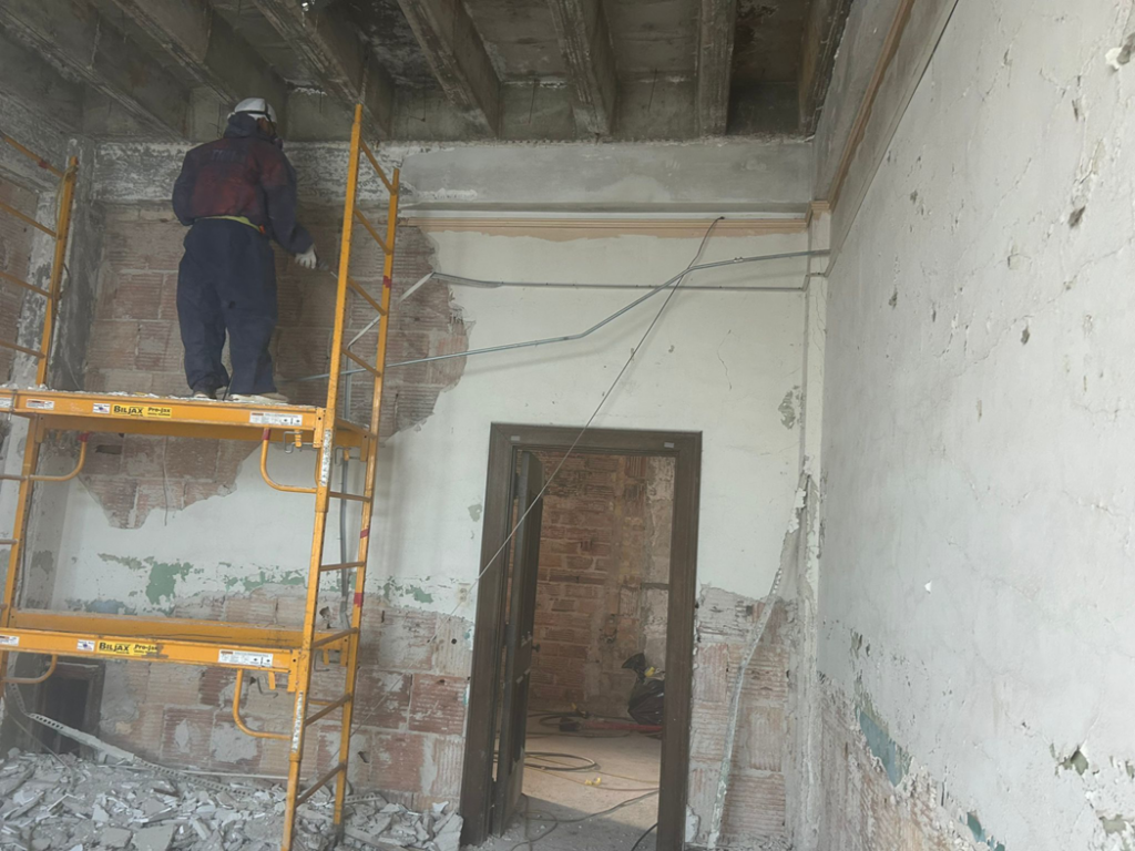 A handyman on scaffolding performing interior wall demolition and renovation for TRM Staffing LLC in Indianapolis, IN.
