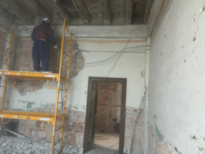 A handyman on scaffolding performing interior wall demolition and renovation for TRM Staffing LLC in Indianapolis, IN.