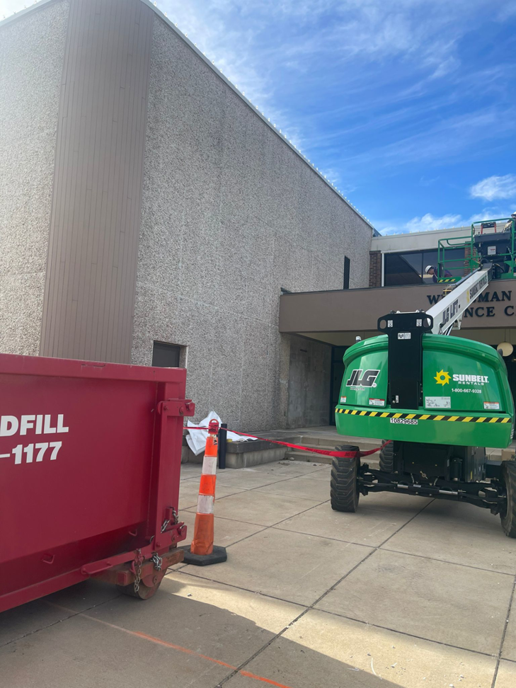 A handyman operating a JLG boom lift for exterior building maintenance by TRM Staffing LLC in Indianapolis, IN.