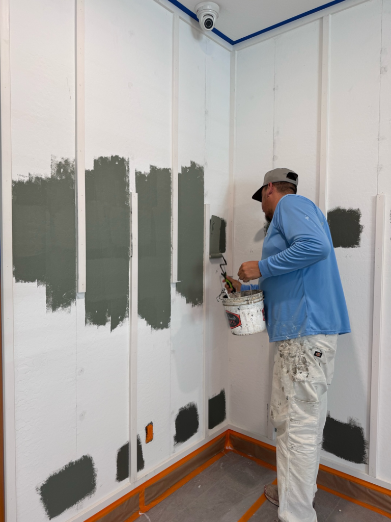 A handyman from State 48 Painting Company LLC painting an interior wall with board and batten paneling in Queen Creek, AZ.