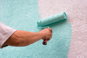 A handyman from Top Ace painting a textured wall with a roller in Atlanta, GA
