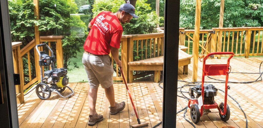 A handyman from Westlake Ace Handyman Services Kansas City Metro power washing a wooden deck in Lenexa, KS.