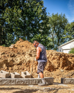 A handyman from White Buffalo Restoration in Nashville, TN, preparing concrete blocks for an outdoor hardscaping project.