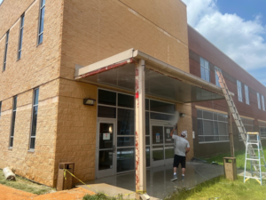 A handyman pressure washing the entrance and awning of a commercial building for Selk Solutions in Crossville, TN.