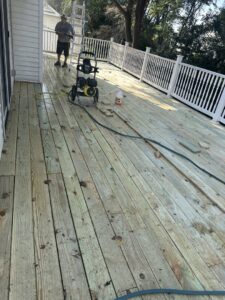 A handyman from Jewell Services pressure washing a wooden deck to clean and restore it in Des Moines, IA.