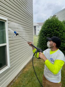 A handyman pressure washing house siding, a service provided by Quality Services, LLC in Alexandria, VA.