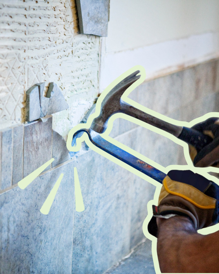 A handyman removing old wall tiles with a hammer and pry bar for Pjai Projects in Nashville, TN