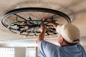 A handyman repairing or installing a large ceiling light fixture with colorful bulbs for Larry's Appliance Repair in California, MO.