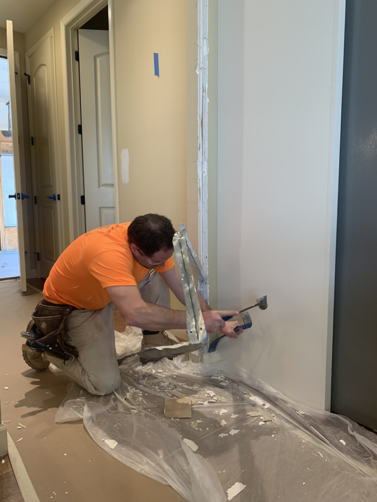 A handyman repairing a drywall or door frame at a client's home by Walrus Rock Construction LLC in Pacific, MO.