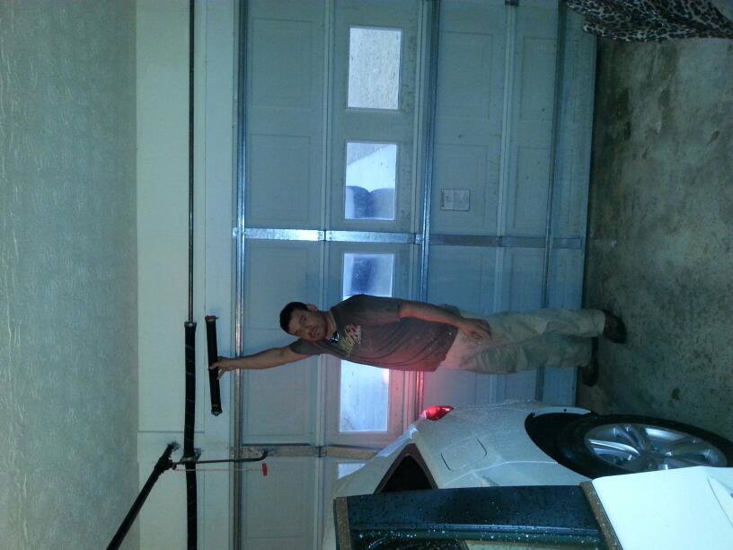 A handyman repairing garage door springs and the track system for Overhead Door Company of Columbus in Columbus, GA.