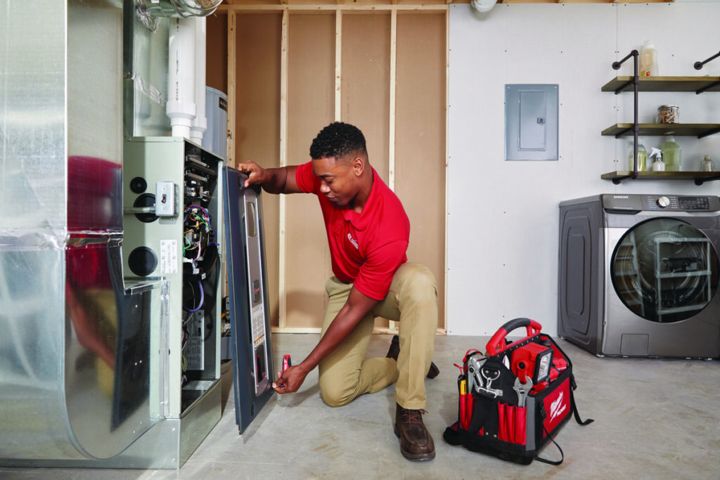 A handyman from Westlake Ace Handyman Services Kansas City Metro repairing an HVAC unit in a utility room in Lenexa, KS.