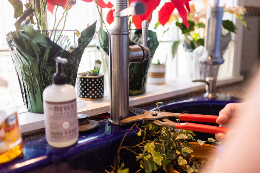 A handyman repairing a kitchen faucet with pliers in a home serviced by Larry's Appliance Repair in California, MO.