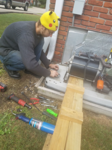 A handyman repairing an outdoor generator for The Lighted Path in Louisville, KY.