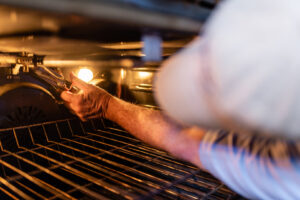 A handyman repairing an oven, reaching inside to fix a component for Larry's Appliance Repair in California, MO.