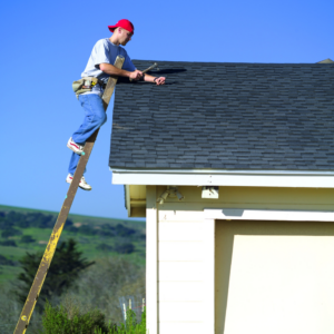 A handyman from A D&D Contracting repairing a shingle roof while on a ladder in Hallsville, MO.