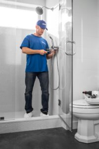 A Handyman Connection technician repairing a shower fixture in a modern bathroom in Fort Collins, CO