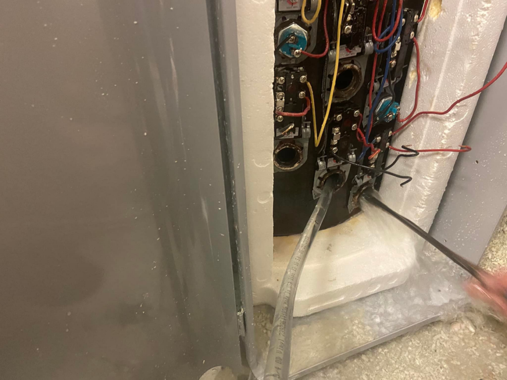 A handyman from Handyman Al repairing a water heater with exposed wiring and components in Rapid City, SD.