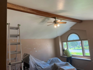 A handyman repairing a window area in a room with walls prepped for painting, provided by Honest Help in Fort Wayne, IN
