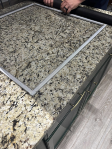 A handyman's hands repairing a window screen, demonstrating a service from JJConstruction203 LLC in Charlotte, NC.