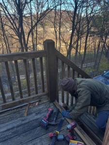 A handyman repairing a wooden deck railing with tools on the deck by The Handyman Gabriel in Madison, WI