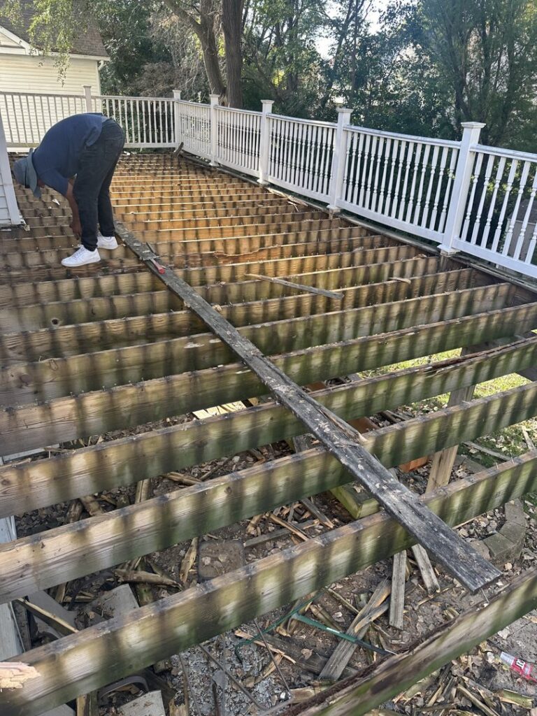 A handyman from Jewell Services repairing a wooden deck, with some boards removed for replacement in Des Moines, IA.