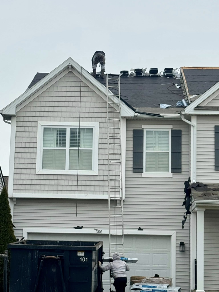 A handyman worker on a ladder replacing a roof for Darby Builders in Columbus, OH.