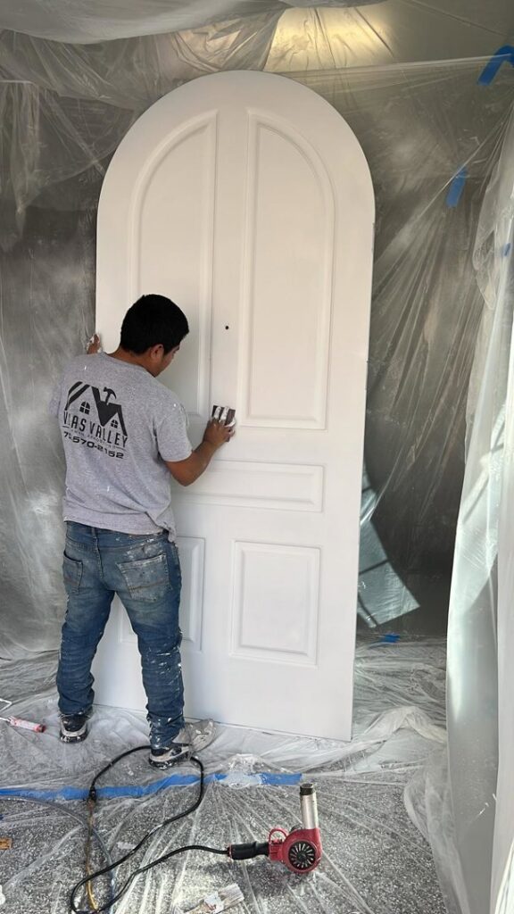 A handyman sanding an arched door, preparing it for painting or refinishing, for Vegas Valley Remodeling/Handy-Man Services in Las Vegas, NV.