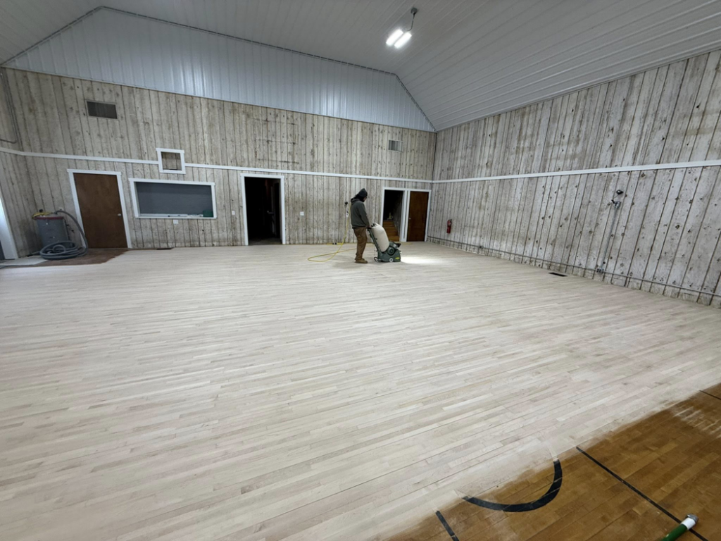 A handyman operating a floor sander to refinish a hardwood floor for Vera Flooring in Grand Rapids, MI.
