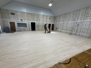A handyman operating a floor sander to refinish a hardwood floor for Vera Flooring in Grand Rapids, MI.