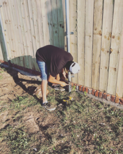 A handyman from Alva Roofing securing a fence post with a drill during installation in Oklahoma City, OK.