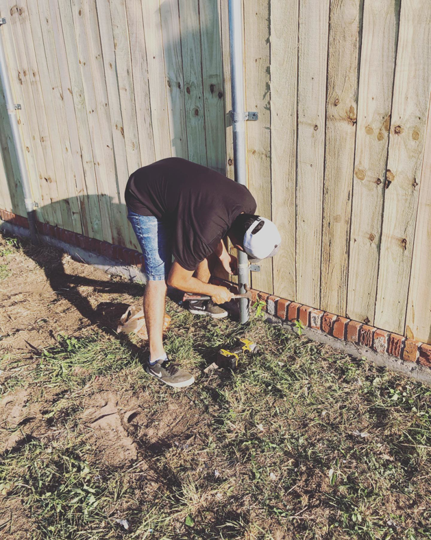 A handyman from Alva Roofing securing a fence post with a drill during installation in Oklahoma City, OK.