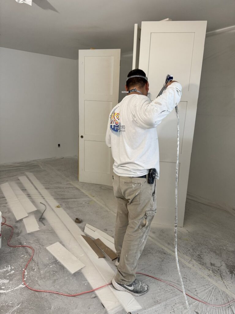 A handyman from State 48 Painting Company LLC spray painting interior doors and trim in Queen Creek, AZ.